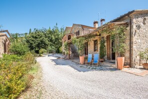 A stone building with a gravel path, wooden doors, and potted plants. - Podere Giardino Wine & Bed – Melograno Apartment: Country House with Pool, Wi-Fi & AC (Montalcino)
