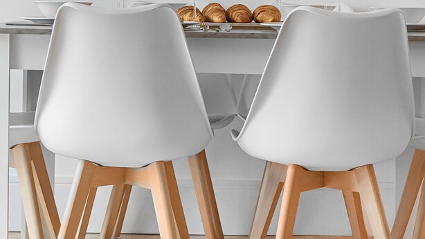 A dining area with a table set for two, two white chairs, and a plate of croissants. - King's Cross Apartment with Terrace (London)