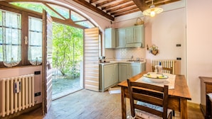 Cozinha rústica com vigas de madeira, uma mesa de jantar e vista para o verde lá fora.