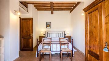 Quarto com estrutura de cama de madeira, duas mesas de cabeceira com luminárias, um radiador e um guarda-roupa de madeira grande.