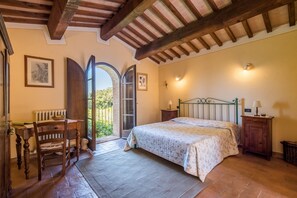 Un dormitorio con cama, una silla, una mesa y un ventanal.