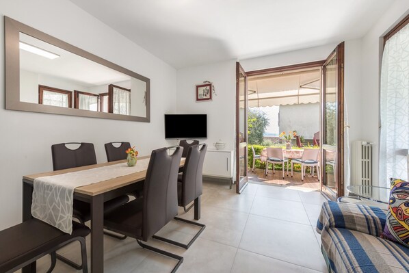 A dining area with a table, chairs, a TV, and a sofa.