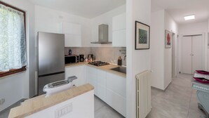A modern kitchen with white cabinets, a stainless steel refrigerator, a microwave, and a gas stove. - Holiday Apartment "Casetta - New Lake" with Private Terrace & Wi-Fi (Gardone Riviera)