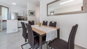 A modern dining area with a wooden table, six chairs, a white tablecloth, and a large mirror on the wall. - Holiday Apartment "Casetta - New Lake" with Private Terrace & Wi-Fi (Gardone Riviera)
