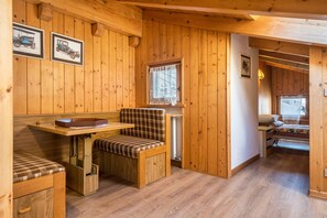 A wooden interior with a bench, table, and a bed.