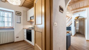Una cocina moderna con armarios de madera, horno empotrado y una ventana con cortina de encaje.