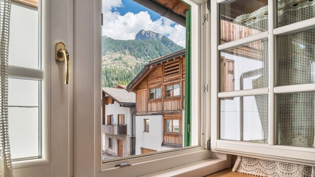 Una ventana con vistas a edificios de madera tradicionales y una montaña.