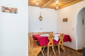 A dining area with a wooden table and chairs, a red tablecloth, and a hanging light fixture.