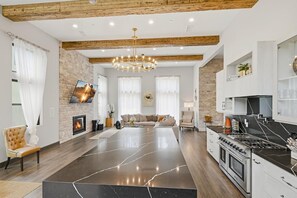 Amplia sala de estar con chimenea, una isla grande y una cocina con estufa.