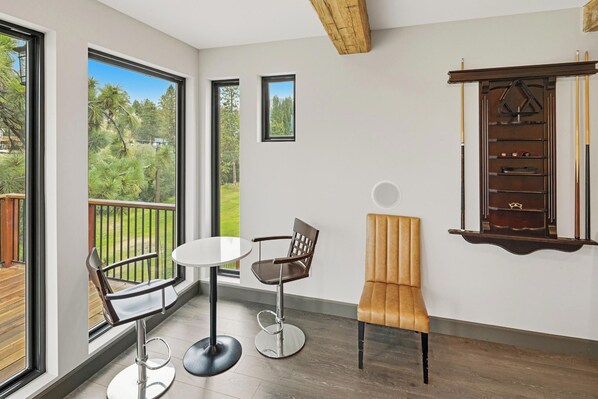A room with a balcony, a pool table, and a chair.