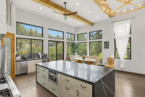 A spacious kitchen with a large island, built-in appliances, and large windows offering views of the outdoors.