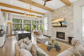 Un amplio espacio habitable con chimenea, un ventanal grande y una cocina moderna.