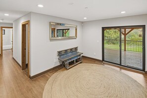 Una habitación amplia con un gran ventanal, un banco de madera y un espejo en la pared.