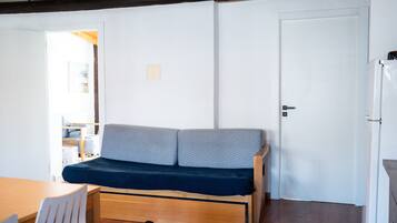 Un espacio habitable compacto con sofá, mesa de comedor y refrigerador.