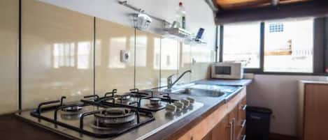 A modern kitchen with a gas stove, stainless steel sink, and wooden cabinets.