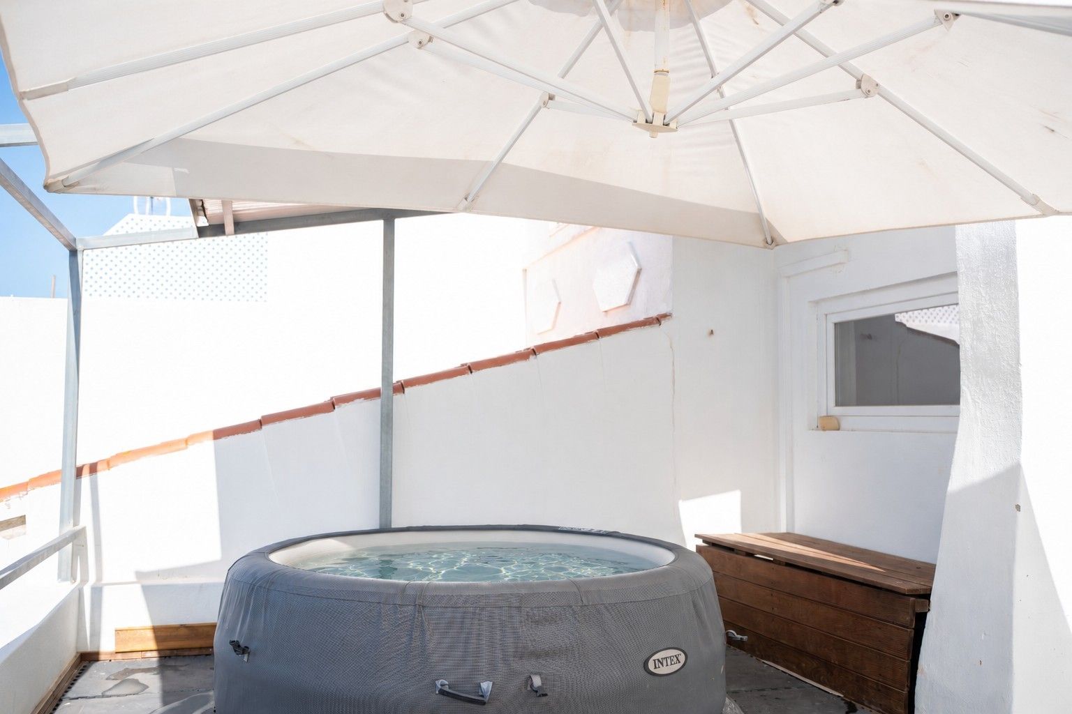 Ein Whirlpool auf einem Balkon mit einem weißen Sonnenschirm darüber.