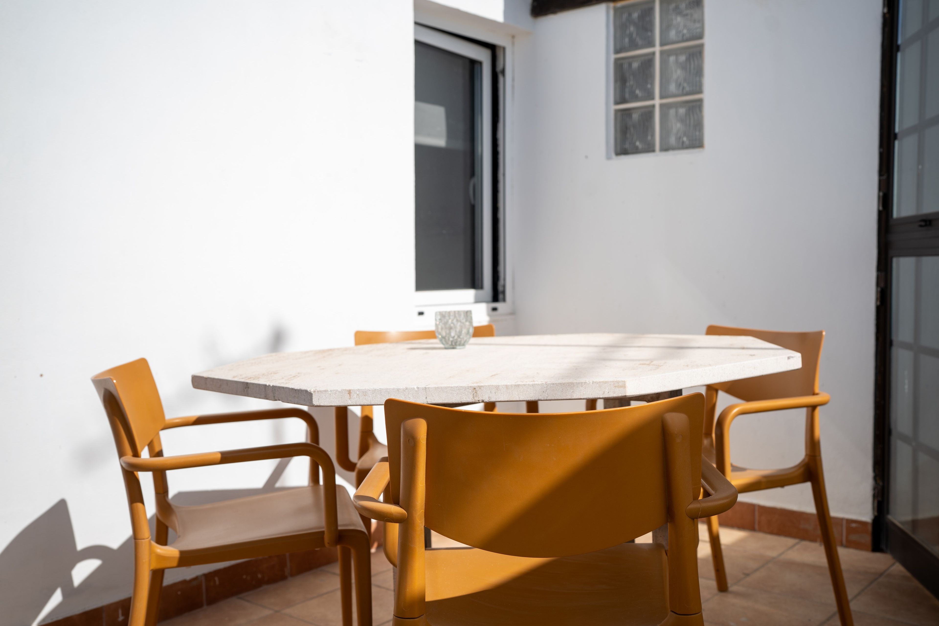 Una mesa redonda con seis sillas, una ventana y una puerta.