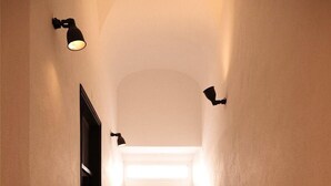 A narrow hallway with a white door at the end, two wall-mounted lights, and a small white object on the floor. - Apartment "Casa na Vila T2" with Shared Terrace & Wi-Fi (Fuseta)