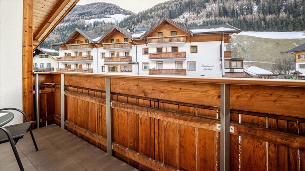 A wooden balcony with a view of a mountain and a hotel building. - Apartment 'Speckign  3' with Mountain View, Balcony and Wi-Fi (Ahrntal)