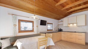 A kitchen with wooden cabinets, a dining table, and a bench. - Apartment 'Speckign  2' with Mountain View, Balcony and Wi-Fi (Ahrntal)