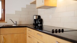 A kitchen with a black countertop, wooden cabinets, a stainless steel sink, and a coffee maker. - Apartment 'Speckign  2' with Mountain View, Balcony and Wi-Fi (Ahrntal)