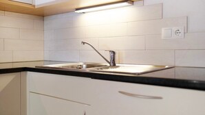 Una cocina moderna con un lavamanos de acero inoxidable, armarios blancos y encimera negra.