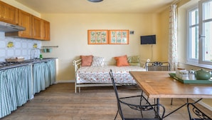 A compact kitchen with a dining area, a bed, and a TV. - Apartment "Il Girasole" with Sea View, Private Terrace and Wi-Fi (Marciana)