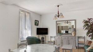 Un comedor con una mesa redonda, sillas, televisor, aparador y sofá.