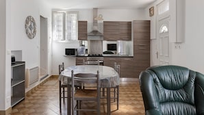 Una cocina moderna con una mesa de comedor y sillas, una butaca de cuero verde y un reloj en la pared.
