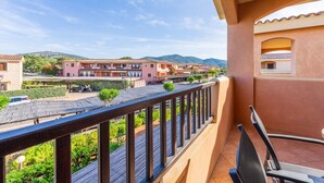 Ein Balkon mit Blick auf ein Wohngebiet, mit Gebäuden und einem Berg im Hintergrund.