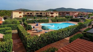 Ein Hotel mit Schwimmbad, umgeben von viel Grün und einer Bergkulisse.