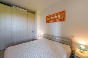 Une chambre à coucher comprenant un lit, des lampes de chevet, une armoire et une œuvre d’art accrochée au mur.