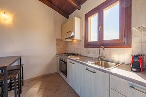 Een koelkast, een oven, een kookplaat, kookgerei, borden en bestek