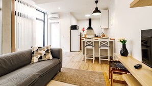 A modern living room with a sofa, a dining table, and a kitchen area in the background. - Apartment 'Ladomar Avenida' with Private Terrace, Private Garden and Wi-Fi (Horta)