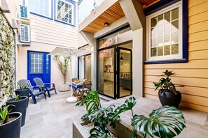 Un edificio moderno con una puerta azul, ventanas grandes y plantas en macetas.