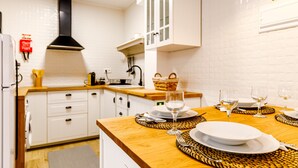 A modern kitchen with white cabinets, a black range hood, and a dining area set with plates and glasses. - Apartment 'Ladomar Avenida' with Private Terrace, Private Garden and Wi-Fi (Horta)