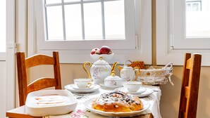 A dining table set with white porcelain tea service, a basket, and a plate of food. - Apartment 'Ladomar Matriz' with Sea View, Private Terrace and Wi-Fi (Horta)