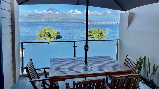 A balcony with a table and chairs, overlooking a body of water and a distant mountain. - Apartment 'Ladomar Matriz' with Sea View, Private Terrace and Wi-Fi (Horta)