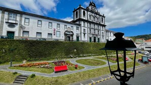 A historic building with a clock tower, surrounded by a landscaped garden with a red bench. - Apartment 'Ladomar Matriz' with Sea View, Private Terrace and Wi-Fi (Horta)