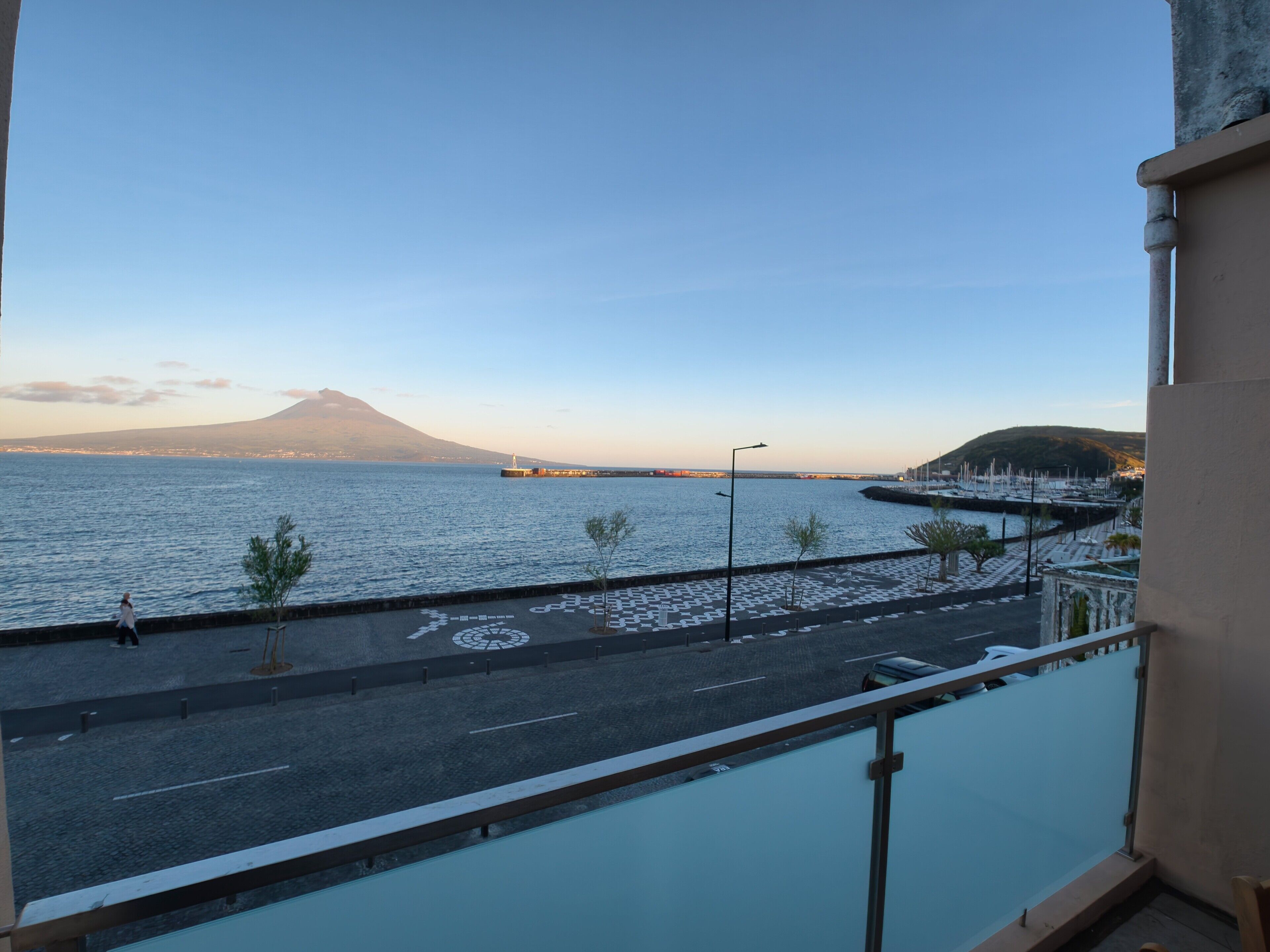 A view from a balcony overlooking a coastal road with a mountain in the background.