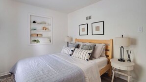 Ein ordentlich eingerichtetes Schlafzimmer mit einem Bett, Nachttischen und Wandregalen.