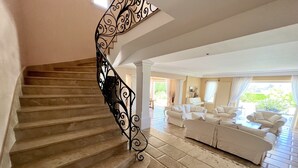A staircase with ornate black railings leading to a living area with a white sofa and a piano. - Cap d'Antibes - Villa 10 people - Swimming pool (Antibes)