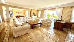 A spacious living room with a large sofa set, a wooden coffee table, and a dining area in the background. - Cap d'Antibes - Villa 10 people - Swimming pool (Antibes)