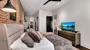 A modern bedroom with a bed, a TV, and a wooden dresser. - Loft Style Spacious Lux Apt 102, sleeps 6 (Atlanta)