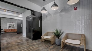 A modern lobby with a wooden floor, two wicker sofas with cushions, a potted plant, and pendant lighting. - Loft Style Spacious Lux Apt 102, sleeps 6 (Atlanta)