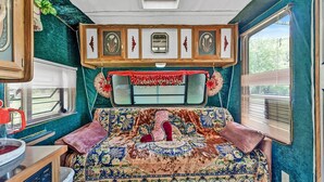 Un ambiente acogedor con una cama, una ventana con persianas, una mesita con hervidor y un ventilador de techo.