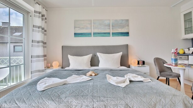 Une chambre d’hôtel avec un lit, un bureau et une vue sur la mer.