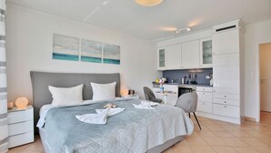 Une chambre moderne avec un grand lit, un bureau et un coin cuisine.