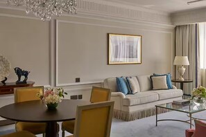A well-appointed living room with a round dining table, a sofa with blue and white cushions, a chandelier, and a framed artwork on the wall. - The Plaza Doha, LXR Hotels & Resorts (DOHA)