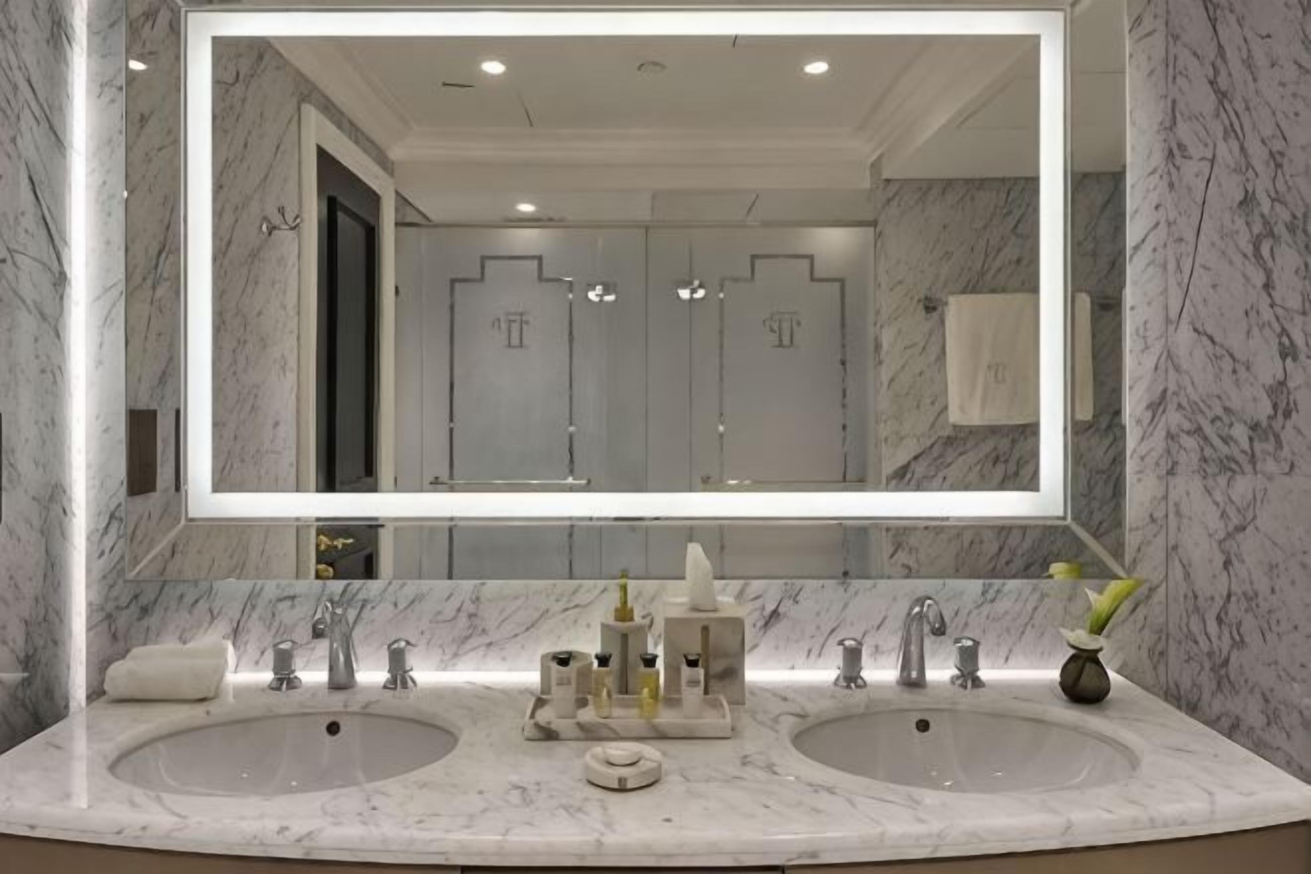 A bathroom with two sinks, a large mirror, and marble walls.